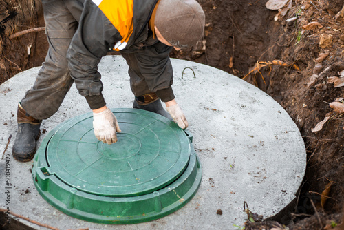 a utility worker lifts a manhole cover for sewerage maintenance and pumping out feces. Septic on a residential lot photo