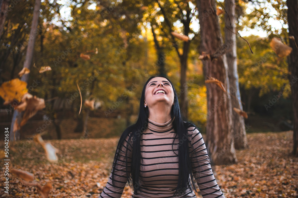 Happy joyful woman having fun throwing autumn fall leaves into the air in the park. Happy joyful woman having fun throwing autumn fall leaves into the air in the park.