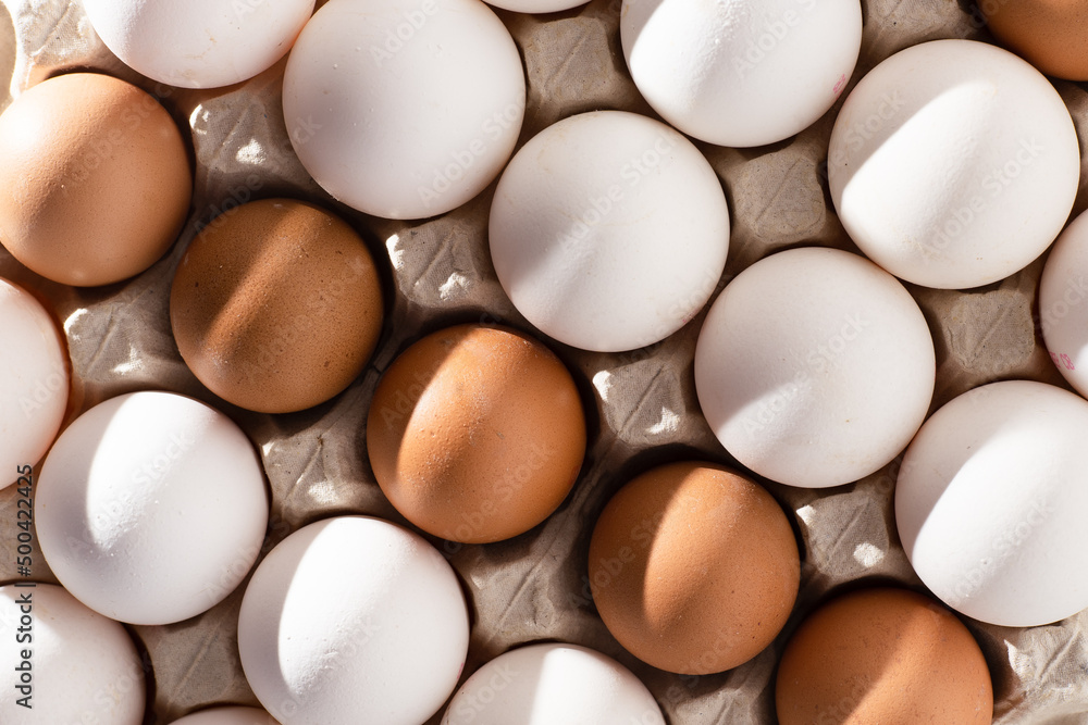 Egg background. White and brown eggs in a paper box tray. Protein food. Eco organic. Minimalism concept. Egg background. White and brown eggs in a paper box tray. Protein food. Eco organic. Minimalism concept.
