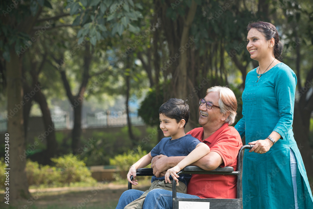 Mother and son with old man in wheelchair at park Mother and son with old man in wheelchair at park