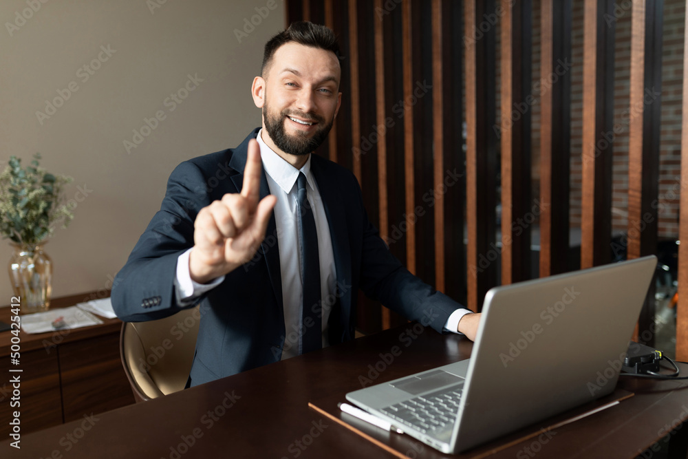 Bank employee in a suit working at a laptop in the office looking at the camera with a smile Bank employee in a suit working at a laptop in the office looking at the camera with a smile