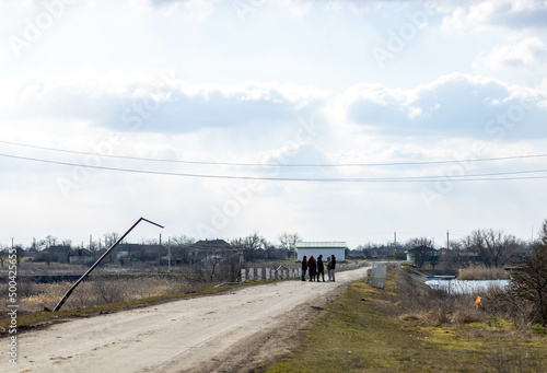 Barmashovo, Ukraine - March 18, 2022: War of Russia against Ukraine. Concept of invasion. People on the river road near destroyed light posts and internet and electricity cables after the battle