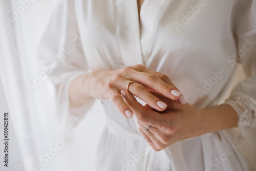 The bride in a silk robe in the morning with a ring on her finger.