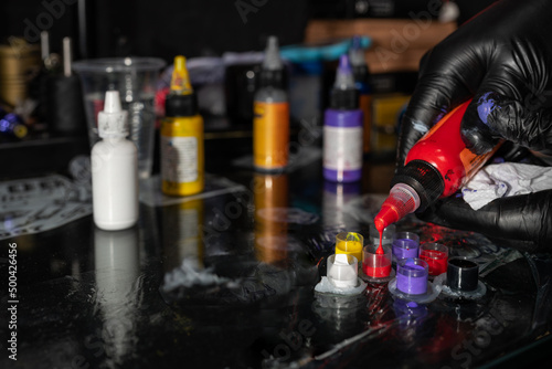 Unrecognizable tattoo master pouring colorful ink