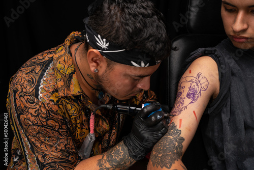 Peruvian tattooist making tattoo on arm of man photo
