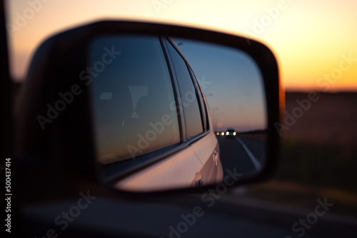 reflection in car rear mirror sunset on the road