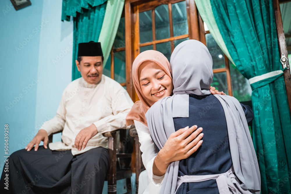 muslim daughter kneel and shake their parent's hand asking for forgiveness on idul fitri celebration at home