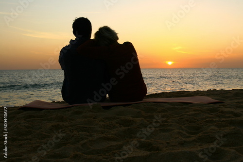 Deux amoureux sur une plage contemplant un magnifique coucher de soleil sur la mer