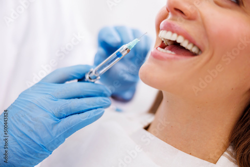 Dentist applying local anesthetic to patient photo
