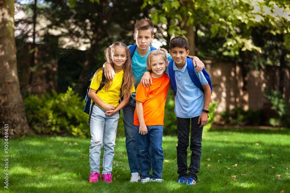 Group of happy school child with schoolbag in outdoor park