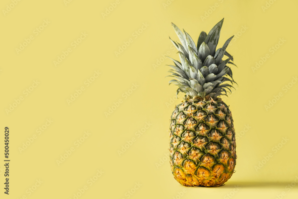 Whole pineapple on the yellow background with copy space for your text. Summertime background with tropic feel