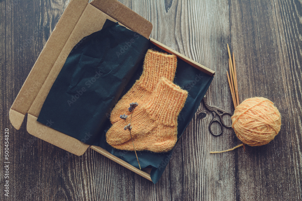 Packing small orange color baby socks, made of organic sheep wool