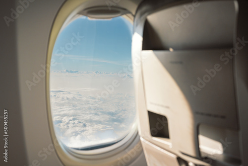 Plane window view with fluffy clouds look in the airplane.Blue sky and white clouds background.Fresh day and the weather is bright.Interior airplane..