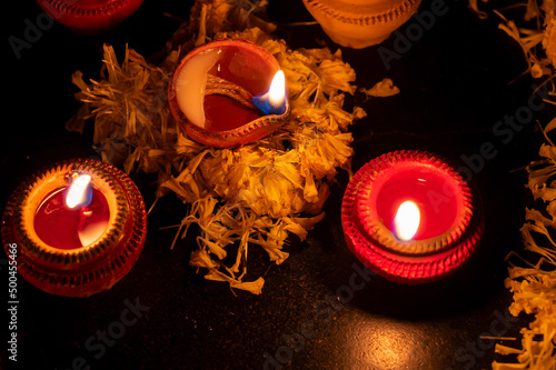 Low angle Rangoli flowers and candles or diyas, Diwali lights at night. Dark background stock image. photo