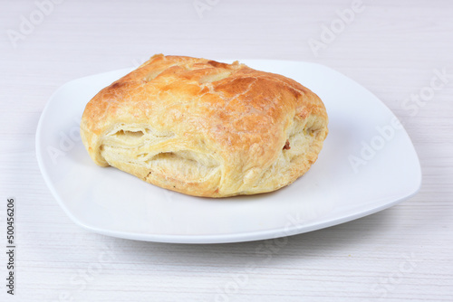 Puff pastry with meat, vegetables and cheese, on a wooden background