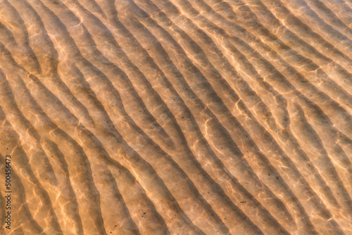 Obraz na płótnie Sandy seabed with wavy pattern under shallow water, abstract texture