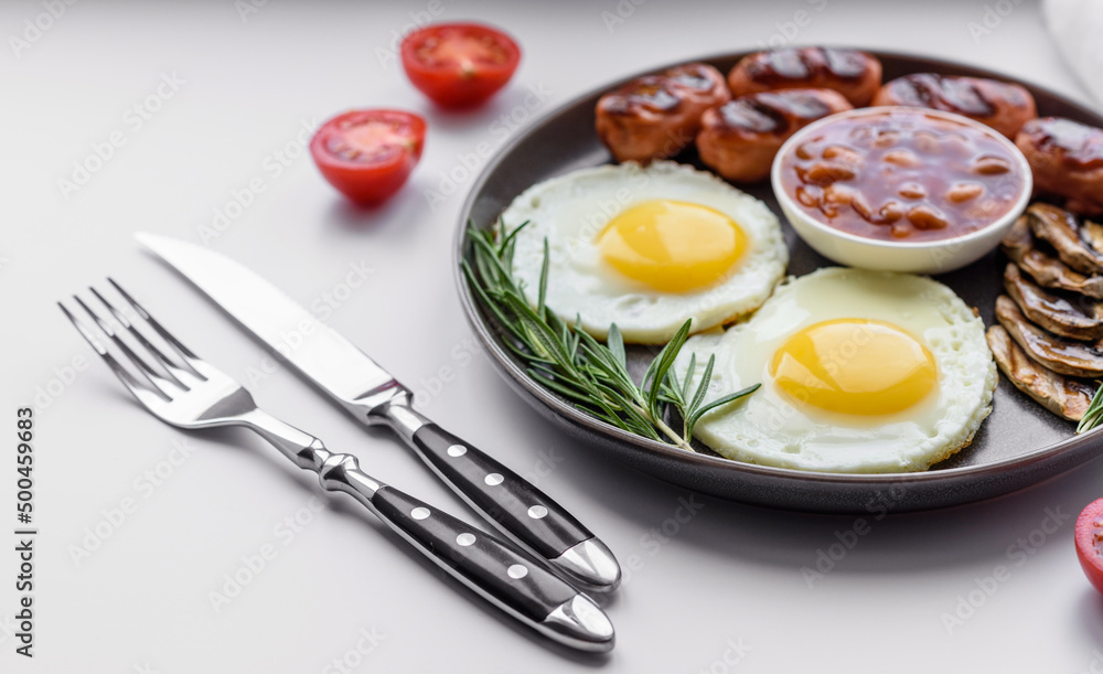 Full english breakfast with bean, fried eggs, roasted sausages, tomatoes and mushrooms Full english breakfast with bean, fried eggs, roasted sausages, tomatoes and mushrooms