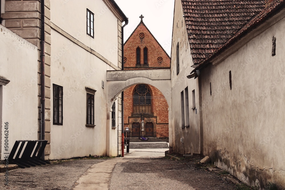A passage between the historical houses with view to the church at Uhercice, Czech republic