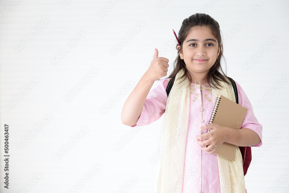cute Indian girl holding notebook for learning and thumbs up pose, education concept cute Indian girl holding notebook for learning and thumbs up pose, education concept