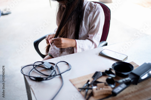 Damaged Hair, frustrated asian young woman, girl hand in holding brush splitting ends messy while combing hair, unbrushed dry long hair. Health care beauty concept. photo