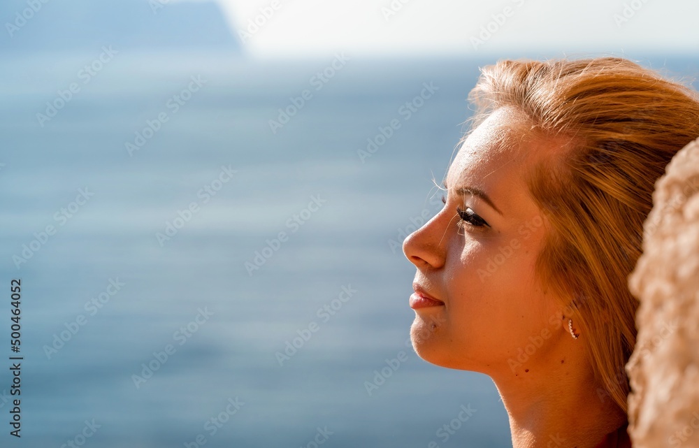 Smiling young woman in a red dress looks at the camera. A beautiful tanned girl enjoys her summer holidays at the sea. Portrait of a stylish carefree woman laughing at the ocean. Smiling young woman in a red dress looks at the camera. A beautiful tanned girl enjoys her summer holidays at the sea. Portrait of a stylish carefree woman laughing at the ocean.