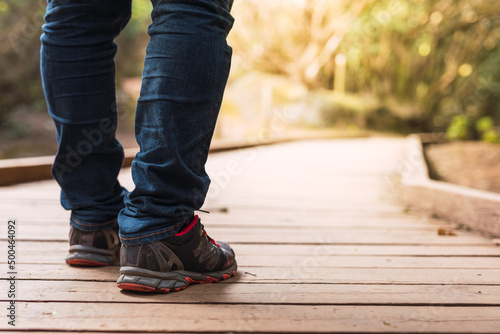Close-up shot of a person's boots walking along a wooden path in the bush