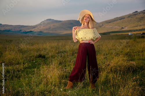 Fashion blonde with a hat posing in the grass