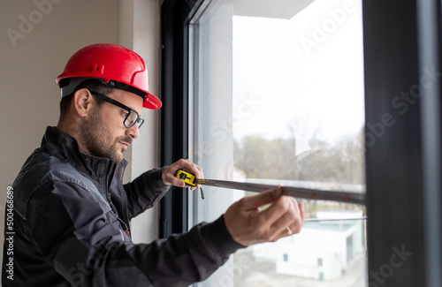 Obraz na płótnie Male worker measuring window with measuring tape.