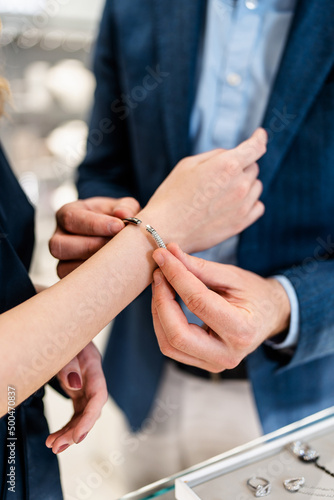 Beautiful couple enjoying in shopping at modern jewelry store. Close up shot of woman's hand with gorgeous expensive ring and bracelet. Selective focus.