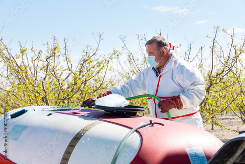 A farmer cleans a chemical spraying tank with water after use