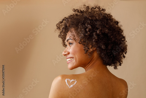 Beautiful lady with curly hairstyle posing against beige wall photo