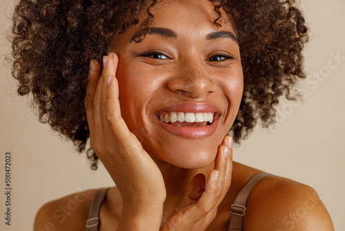 Young woman toothy smiling on beige background of studio