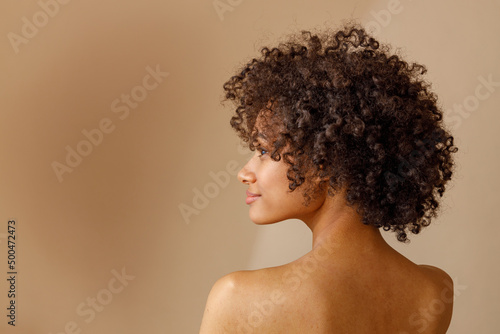 Charming multiracial woman posing against beige wall