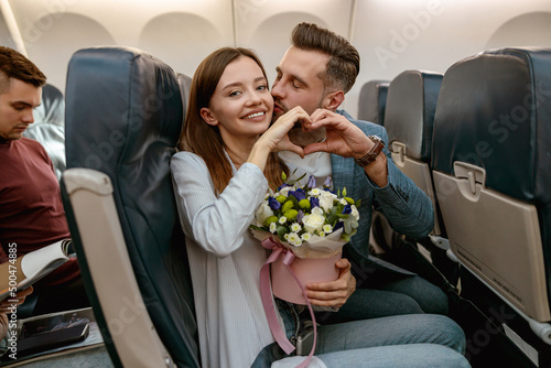Happy couple in love showing heart symbol in airplane