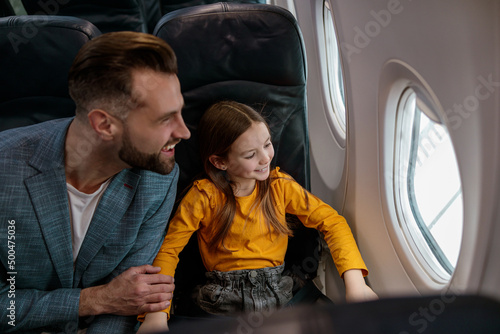 Happy father and daughter looking out airplane window