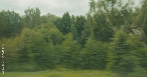View from the window of a moving train of fields and forests on warm summer day
