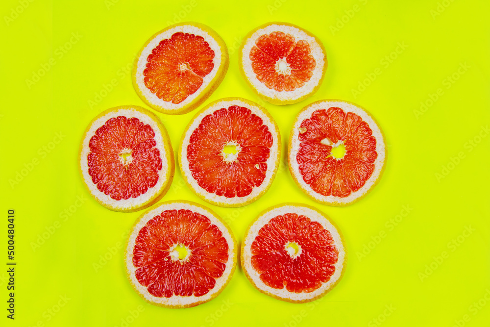 Rings of cut red Grapefruit (Latin Cītrus paradīsi) on a bright yellow background. Vegetables, fruits, healthy foods. Rings of cut red Grapefruit (Latin Cītrus paradīsi) on a bright yellow background. Vegetables, fruits, healthy foods.