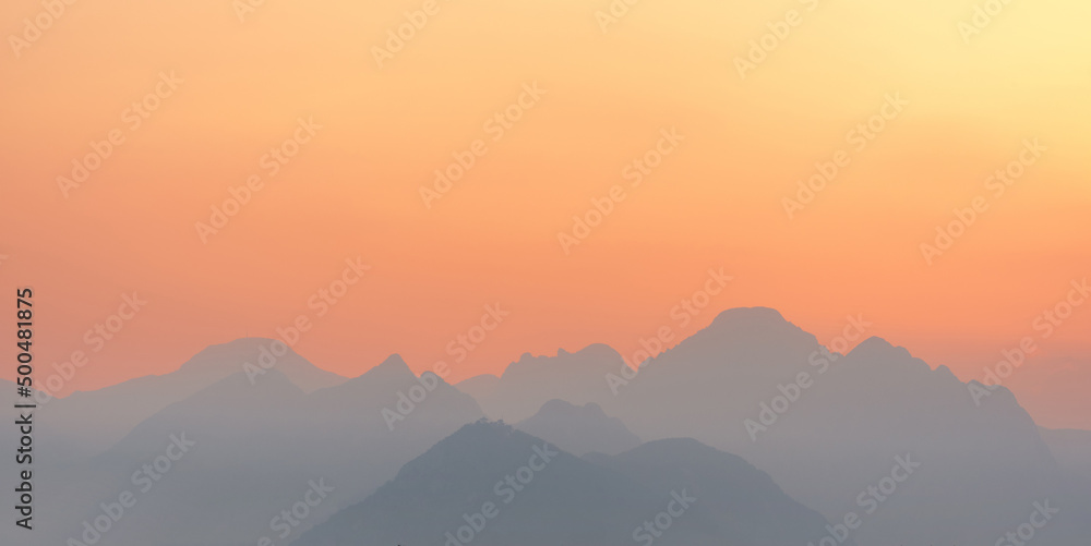bright sunset or sunrise sky with misty mountains