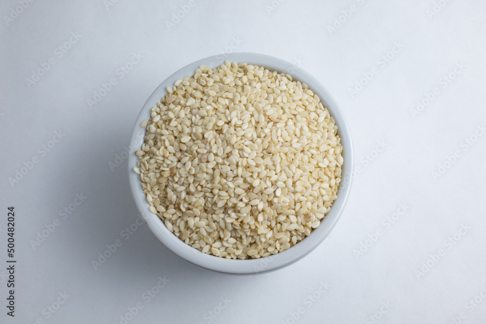 Top view of white sesame seeds (Sesamum indicum), still raw inside small ceramic bowl Top view of white sesame seeds (Sesamum indicum), still raw inside small ceramic bowl