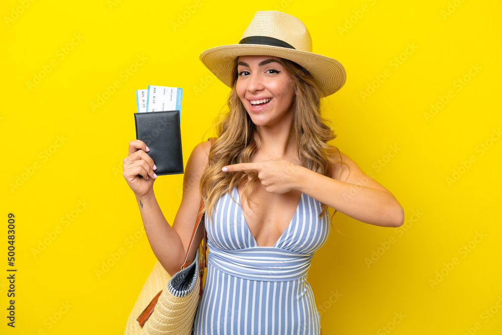 Young woman goes on vacation to the beach isolated on yellow background and pointing it Young woman goes on vacation to the beach isolated on yellow background and pointing it