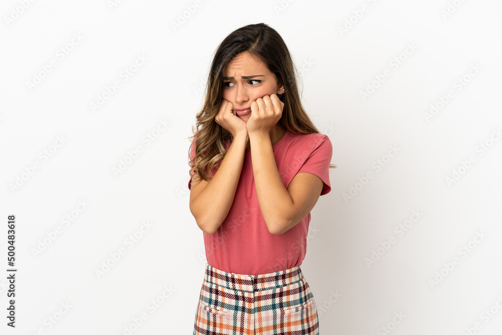 Young woman over isolated background nervous and scared putting hands to mouth