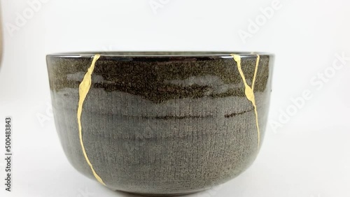 Kintsugi, Gold cracks slow motion detail video, broken greenbowl, Japanese technique, isolated kintsukuroi. photo