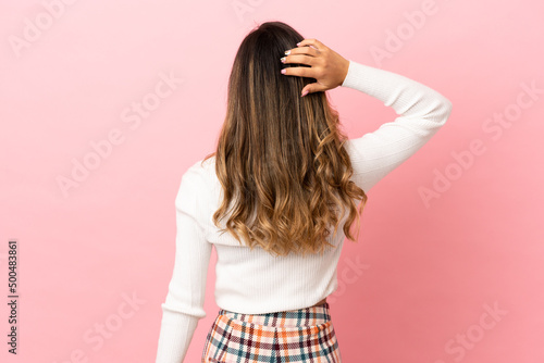 Young woman over isolated background in back position and thinking