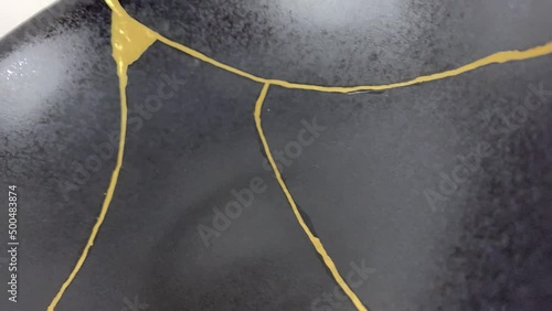 The making of kintsugi, artisan making kintsugi process. Slow motion cinematic video. Black Kintsukuroi bowl.
Closeup isolated.