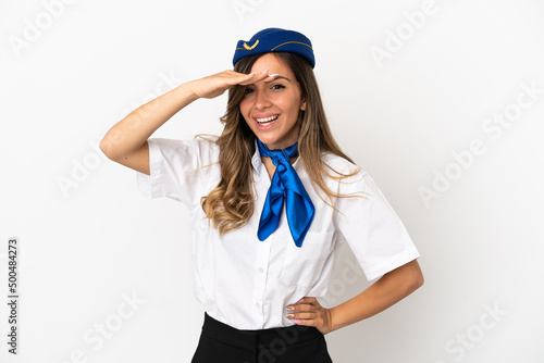 Airplane stewardess over isolated white background looking far away with hand to look something