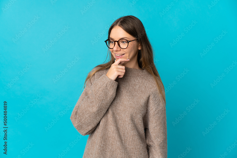Young Lithuanian woman isolated on blue background looking to the side and smiling