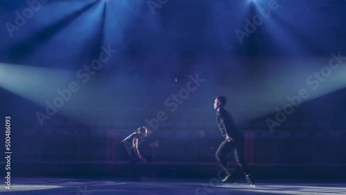 Throw and jump technique in pair figure skating, slow motion.Skaters make compulsory element, Male partner throws woman into air,she makes several turns, gently lands on ice.Flying spinning in jump. photo