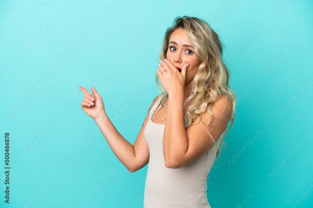 Fototapeta premium Young Brazilian woman isolated on blue background with surprise expression while pointing side