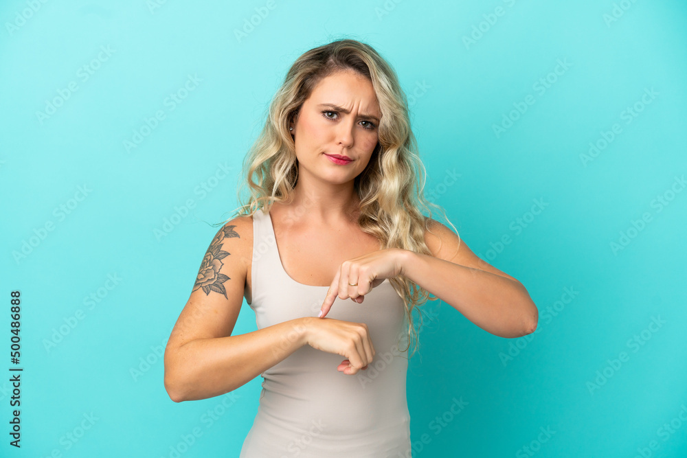 Young Brazilian woman isolated on blue background making the gesture of being late Young Brazilian woman isolated on blue background making the gesture of being late