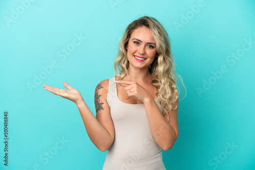 Young Brazilian woman isolated on blue background holding copyspace imaginary on the palm to insert an ad © luismolinero